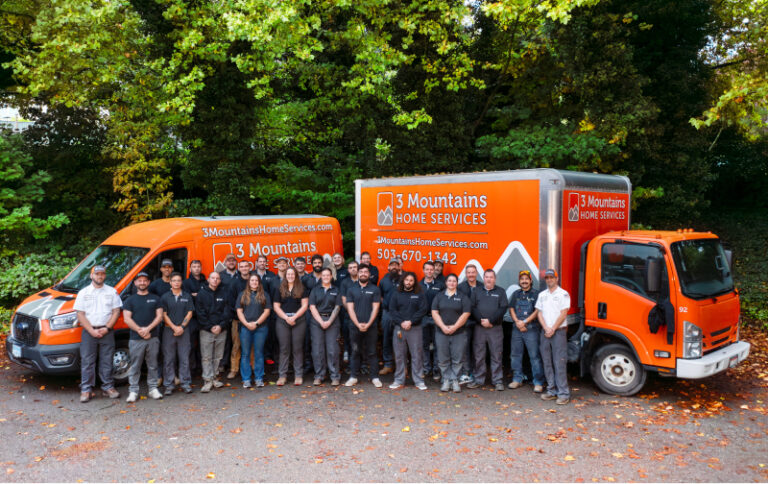 Team photo standing in front of 3 Mountain work trucks